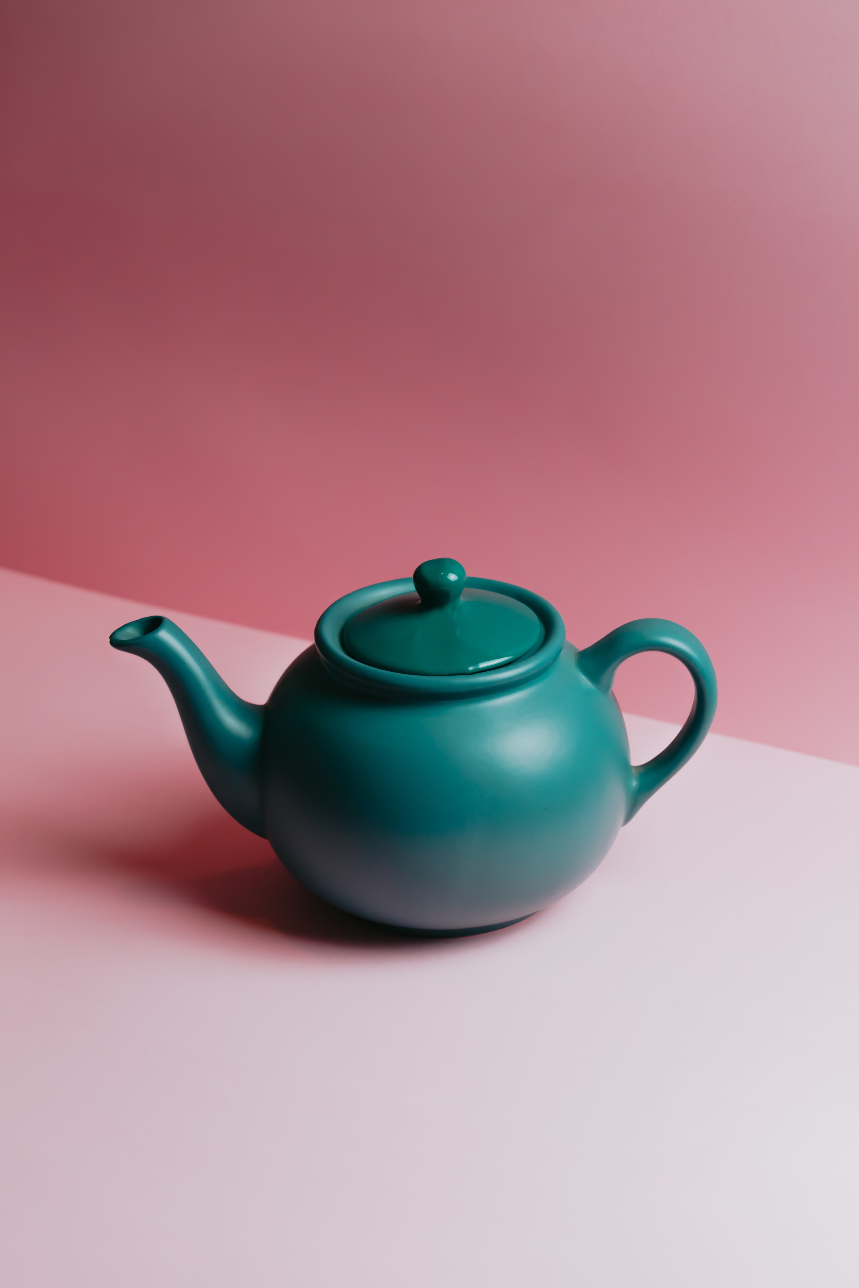 Teapot against a lit pink background.